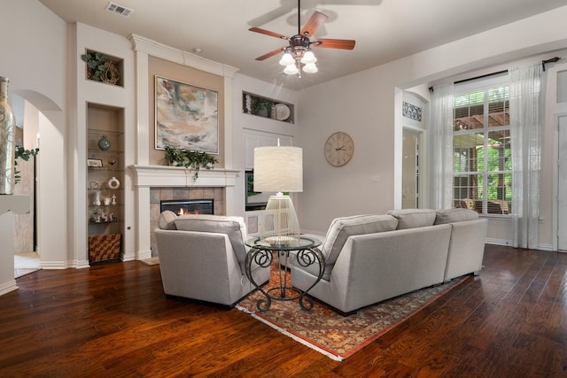 1869 Rio Blanco Dr, Frisco, TX 75033 - living room with dark wood-type flooring, a tile fireplace, ceiling fan, baseboards, and arched walkways