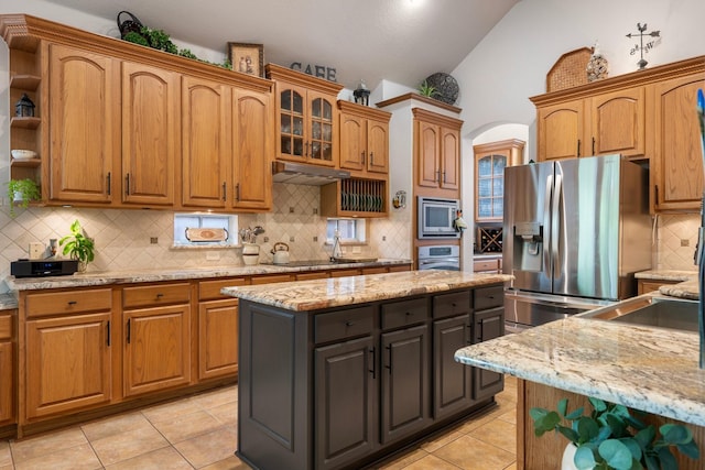 1869 Rio Blanco Dr, Frisco, TX 75033 - kitchen featuring stainless steel appliances, vaulted ceiling, arched walkways, decorative backsplash, and light tile patterned floors
