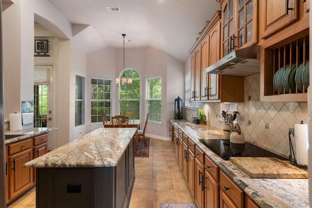 1869 Rio Blanco Dr, Frisco, TX 75033 - kitchen with black electric stovetop, decorative backsplash, brown cabinets, a kitchen island, and glass insert cabinets