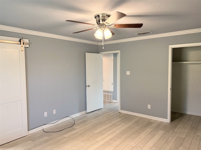 1111 Joel St, Groesbeck, TX 76642 - unfurnished bedroom with light wood-style floors, crown molding, a closet, a barn door, and ceiling fan