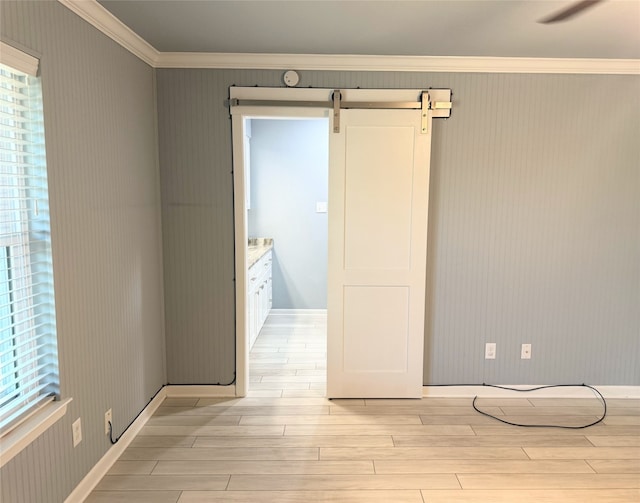 1111 Joel St, Groesbeck, TX 76642 - unfurnished room featuring ornamental molding, light wood-style flooring, a barn door, plenty of natural light, and wallpapered walls