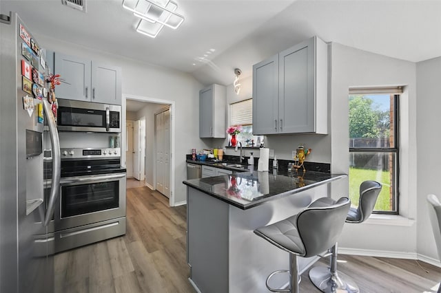 2701 Mims St, Fort Worth, TX 76112 - kitchen featuring appliances with stainless steel finishes, lofted ceiling, wood finished floors, a breakfast bar area, and baseboards