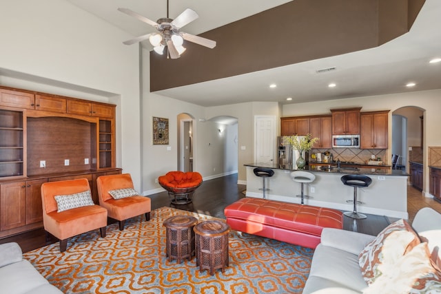 5736 New Castle Dr, Richardson, TX 75082 - living area featuring arched walkways, a ceiling fan, dark wood-style flooring, recessed lighting, and a towering ceiling
