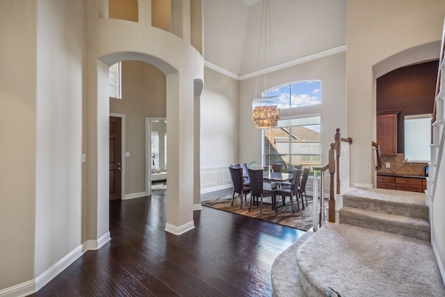 5736 New Castle Dr, Richardson, TX 75082 - dining room with arched walkways, a high ceiling, dark wood-style floors, a chandelier, and baseboards