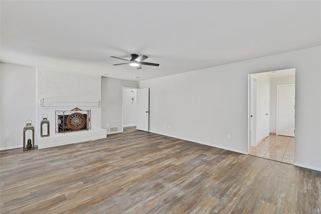 1603 Versailles Dr, Richardson, TX 75081 - unfurnished living room with ceiling fan, wood finished floors, a brick fireplace, and baseboards