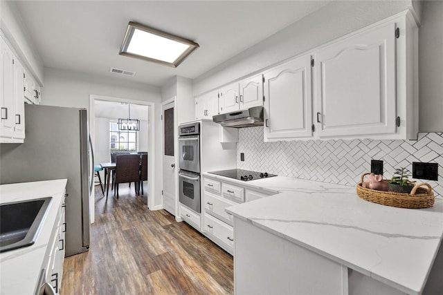 1603 Versailles Dr, Richardson, TX 75081 - kitchen featuring appliances with stainless steel finishes, under cabinet range hood, white cabinets, a chandelier, and wood finished floors
