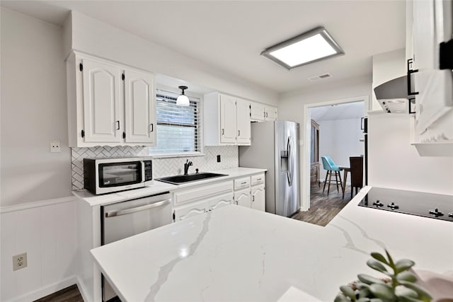 1603 Versailles Dr, Richardson, TX 75081 - kitchen with stainless steel appliances, a sink, dark wood finished floors, white cabinetry, and backsplash