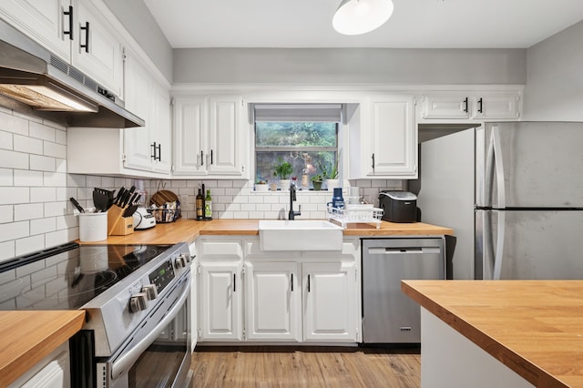 223 Mccarley Pl, Mckinney, TX 75071 - kitchen with butcher block countertops, stainless steel appliances, a sink, under cabinet range hood, and white cabinetry
