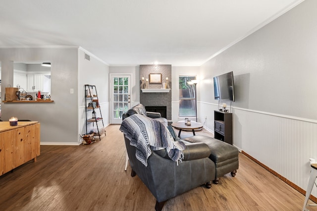 223 Mccarley Pl, Mckinney, TX 75071 - living area featuring wood finished floors, a brick fireplace, baseboards, and crown molding