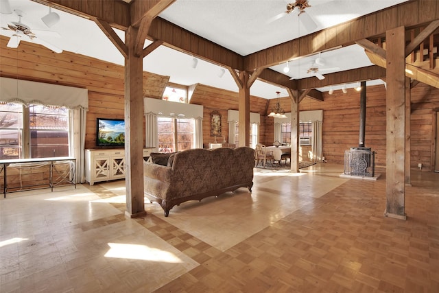 691 Bear Rd, Van Alstyne, TX 75495 - living area with ceiling fan, wooden walls, a high ceiling, a wood stove, and plenty of natural light