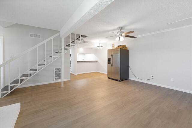 3121 Park Ln Unit 1146, Dallas, TX 75220 - unfurnished living room with stairs, ceiling fan, light wood-style floors, baseboards, and a textured ceiling