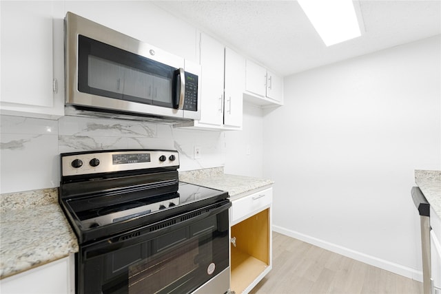 3121 Park Ln Unit 1146, Dallas, TX 75220 - kitchen featuring stainless steel microwave, electric range oven, light wood finished floors, tasteful backsplash, and white cabinetry