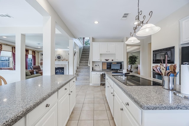 6720 Grant Ln, Plano, TX 75024 - kitchen featuring black appliances, light tile patterned floors, light stone counters, a fireplace, and recessed lighting