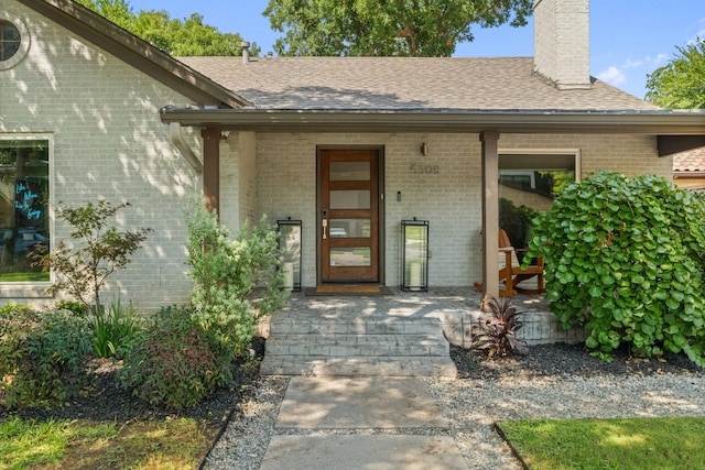 5308 Parkland Ave, Dallas, TX 75235 - view of exterior entry featuring brick siding, covered porch, a chimney, and roof with shingles