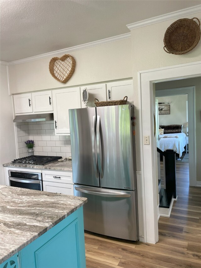 2620 County Road 1102, Grandview, TX 76050 - kitchen with appliances with stainless steel finishes, ornamental molding, wood finished floors, white cabinetry, and decorative backsplash
