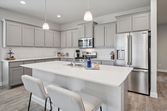 5213 Meadow Ln, Krum, TX 76249 - kitchen featuring gray cabinets, stainless steel appliances, light wood-style flooring, a kitchen bar, and pendant lighting