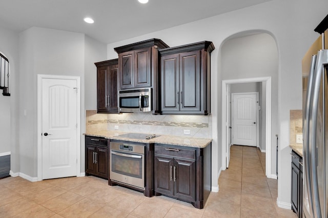 417 Sagebrush Ln, Waxahachie, TX 75165 - kitchen featuring stainless steel appliances, dark brown cabinetry, light stone countertops, light tile patterned floors, and tasteful backsplash