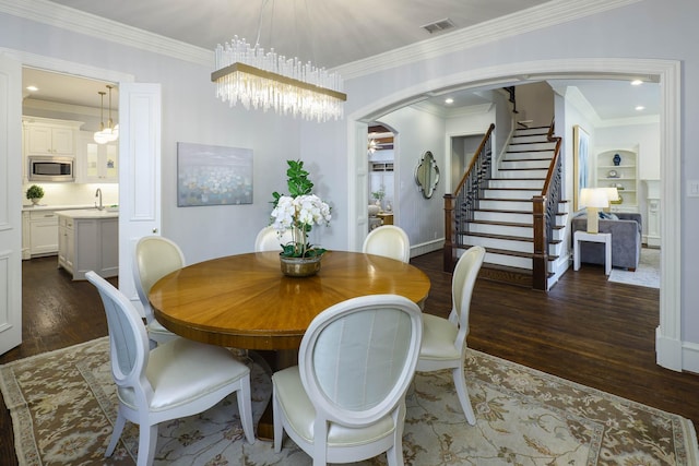 2900 Amherst Ave, University Park, TX 75225 - dining space featuring wood finished floors, stairway, a chandelier, crown molding, and arched walkways