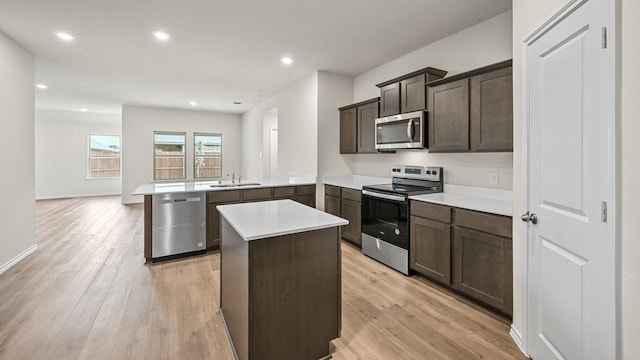 504 Drake Dr, Ferris, TX 75125 - kitchen with appliances with stainless steel finishes, a peninsula, a center island, light wood-style flooring, and dark brown cabinetry