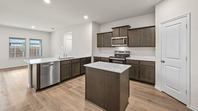 504 Drake Dr, Ferris, TX 75125 - kitchen featuring stainless steel appliances, a peninsula, dark brown cabinetry, light wood-style flooring, and light countertops