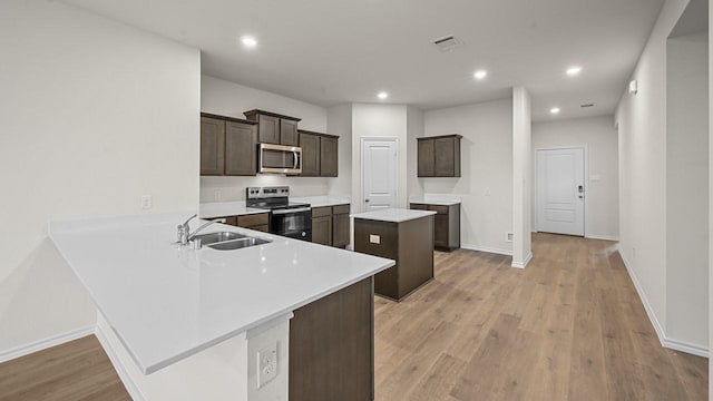 504 Drake Dr, Ferris, TX 75125 - kitchen with appliances with stainless steel finishes, dark brown cabinetry, light wood-type flooring, light countertops, and a peninsula