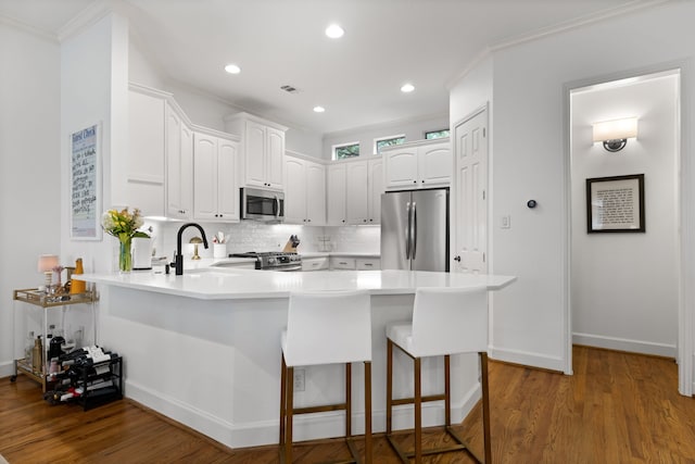 2408 Wild Cherry Way, Dallas, TX 75206 - kitchen featuring stainless steel appliances, a peninsula, a sink, decorative backsplash, and wood finished floors