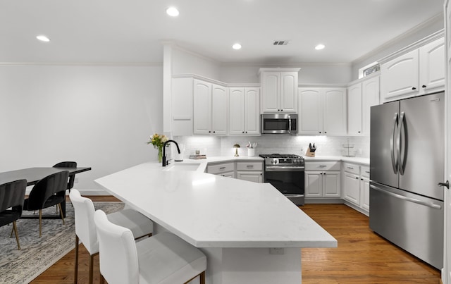 2408 Wild Cherry Way, Dallas, TX 75206 - kitchen with stainless steel appliances, a sink, a peninsula, a breakfast bar area, and decorative backsplash