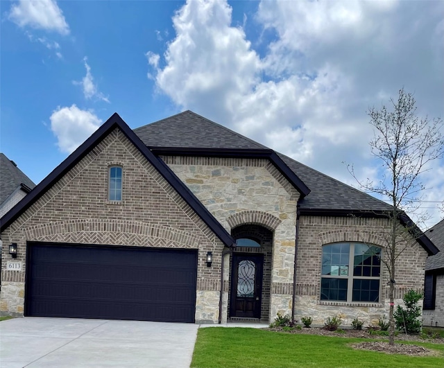 6113 Rodin Dr, Royse City, TX 78189 - french country style house with a shingled roof, stone siding, brick siding, and concrete driveway