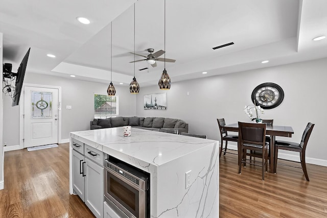 3039 Dutton Dr, Dallas, TX 75211 - kitchen with stainless steel microwave, a tray ceiling, ceiling fan, light wood finished floors, and light stone countertops