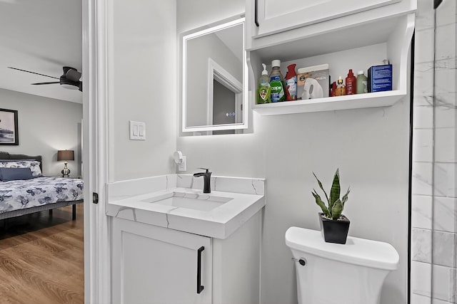 3039 Dutton Dr, Dallas, TX 75211 - bathroom with toilet, vanity, wood finished floors, ceiling fan, and ensuite bath