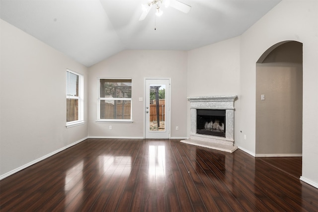 648 Tabasco Trl, Arlington, TX 76002 - unfurnished living room featuring ceiling fan, a fireplace with raised hearth, wood finished floors, vaulted ceiling, and arched walkways