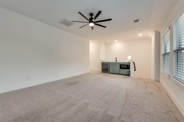 12104 Fairway Meadows Dr, Fort Worth, TX 76179 - unfurnished living room with bar with sink, wine cooler, a ceiling fan, light colored carpet, and recessed lighting