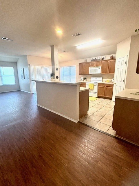 8309 Horse Whisper Ln, Fort Worth, TX 76131 - kitchen featuring white appliances, light wood finished floors, light countertops, brown cabinets, and baseboards