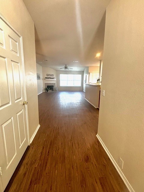 8309 Horse Whisper Ln, Fort Worth, TX 76131 - unfurnished living room featuring baseboards, dark wood-style flooring, ceiling fan, and a fireplace