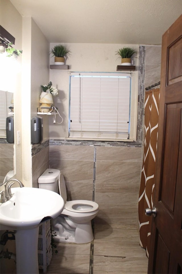 612 Ranier Cir, Garland, TX 75041 - half bath with tile walls, toilet, wood finished floors, a sink, and wainscoting
