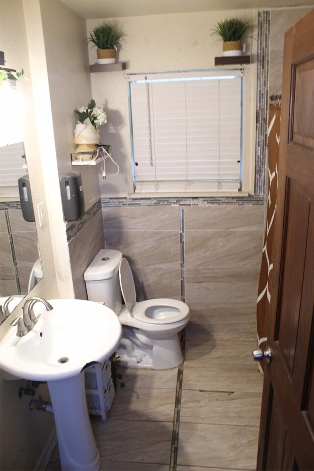 612 Ranier Cir, Garland, TX 75041 - bathroom featuring tile walls, toilet, and a wainscoted wall