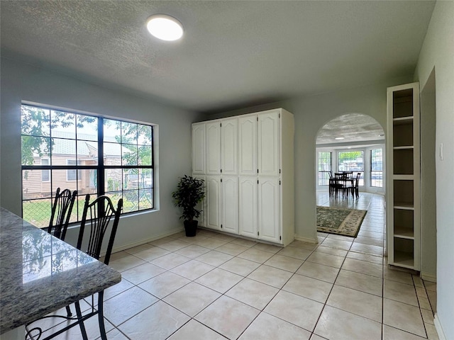 3107 Hale Ave, Fort Worth, TX 76106 - dining room featuring arched walkways, light tile patterned floors, a textured ceiling, and baseboards