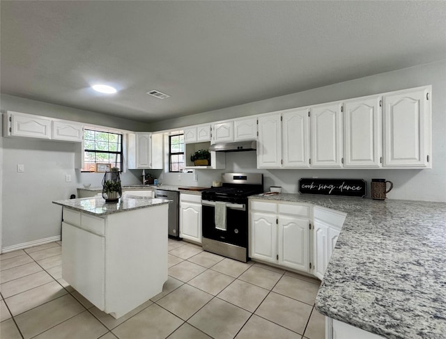 3107 Hale Ave, Fort Worth, TX 76106 - kitchen featuring appliances with stainless steel finishes, under cabinet range hood, white cabinetry, light stone counters, and light tile patterned floors