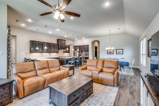 9820 Surveyor Rd, Little Elm, TX 75068 - living room with arched walkways, a ceiling fan, a chandelier, light wood finished floors, and vaulted ceiling