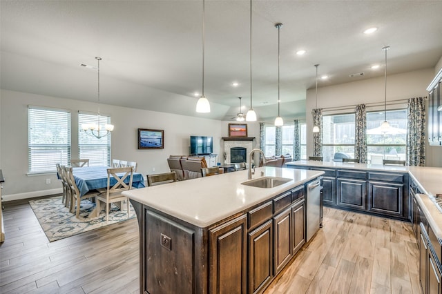 9820 Surveyor Rd, Little Elm, TX 75068 - kitchen with a sink, light wood-style flooring, a stone fireplace, light countertops, and a center island with sink