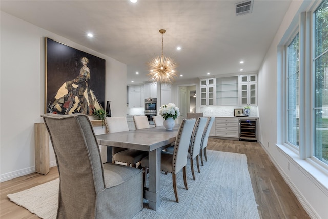 11207 Dwarfs Cir, Dallas, TX 75229 - dining area with wine cooler, light wood-type flooring, a chandelier, recessed lighting, and bar