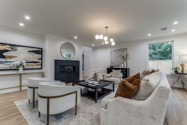 11207 Dwarfs Cir, Dallas, TX 75229 - living room with recessed lighting, light wood finished floors, a glass covered fireplace, and a chandelier