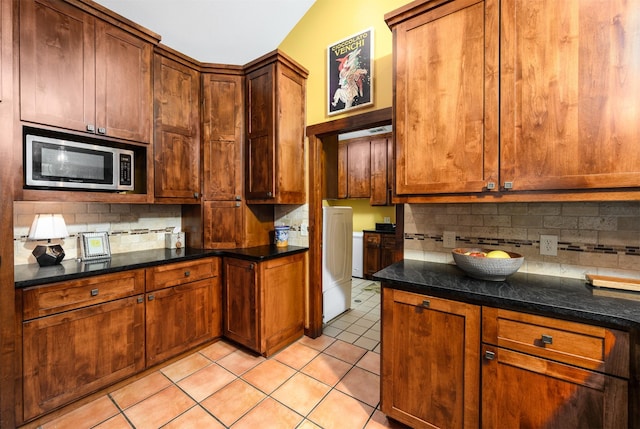 17889 County Road 134, Flint, TX 75762 - kitchen featuring stainless steel microwave, decorative backsplash, light tile patterned floors, dark countertops, and washer / clothes dryer