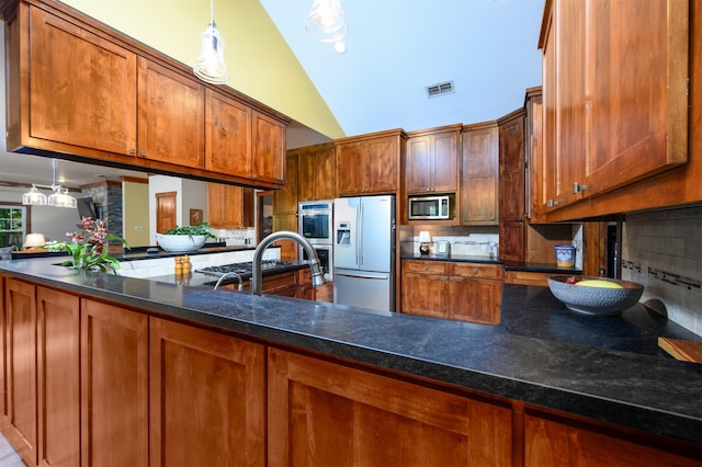 17889 County Road 134, Flint, TX 75762 - kitchen featuring appliances with stainless steel finishes, decorative backsplash, brown cabinets, a peninsula, and high vaulted ceiling