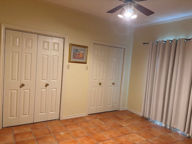 17889 County Road 134, Flint, TX 75762 - unfurnished bedroom featuring two closets, ornamental molding, baseboards, light tile patterned flooring, and a ceiling fan