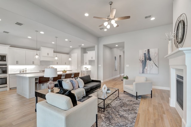504 Arrowhead Ln, Haslet, TX 76052 - living area with light wood-style floors, a ceiling fan, a fireplace, and recessed lighting