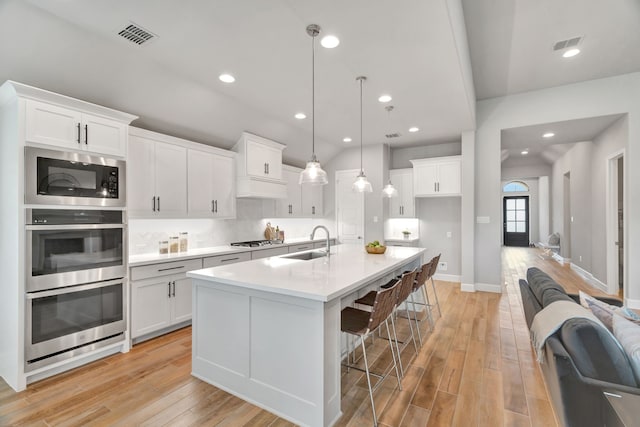 504 Arrowhead Ln, Haslet, TX 76052 - kitchen featuring appliances with stainless steel finishes, white cabinets, light wood finished floors, a breakfast bar area, and recessed lighting