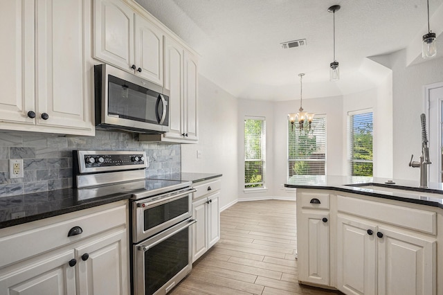 2109 Timber Cove Ct, Weatherford, TX 76087 - kitchen with stainless steel appliances, a chandelier, tasteful backsplash, light wood-style floors, and decorative light fixtures