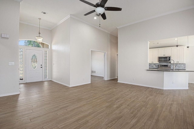 2109 Timber Cove Ct, Weatherford, TX 76087 - entrance foyer with ceiling fan, wood finished floors, a towering ceiling, baseboards, and ornamental molding
