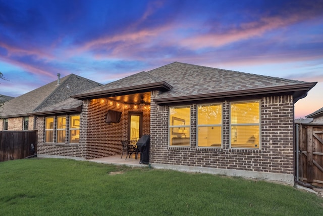 10113 Warberry Trl, Fort Worth, TX 76131 - back of house at dusk with brick siding, a shingled roof, and a patio area